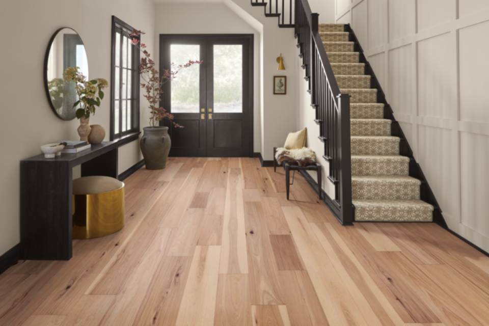 light hardwood flooring in entryway with brown accent furniture and stairs.